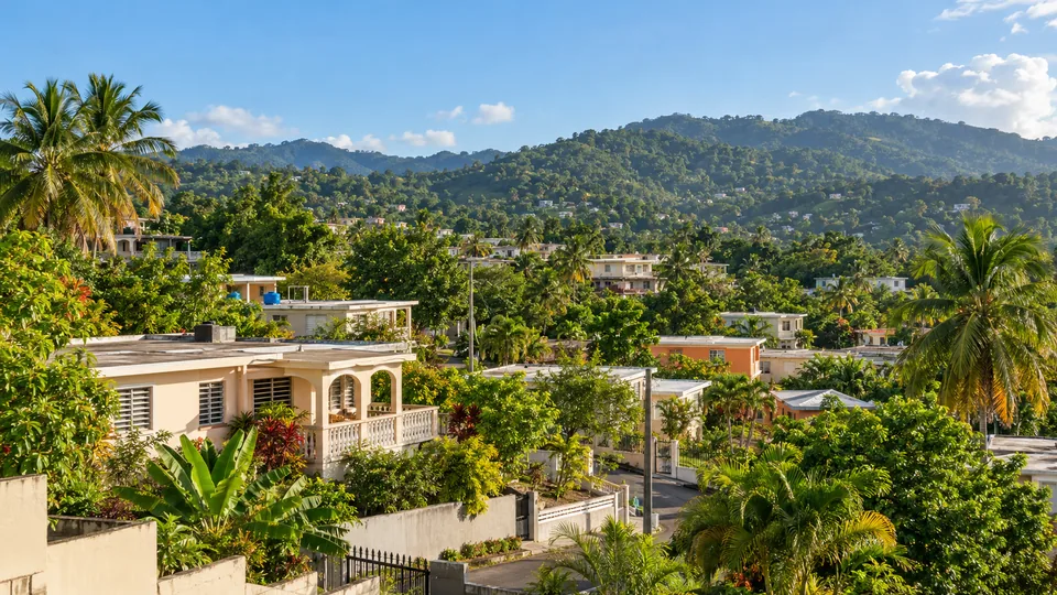 Vista representativa de un vecindario residencial puertorriqueño rodeado de vegetación y montañas