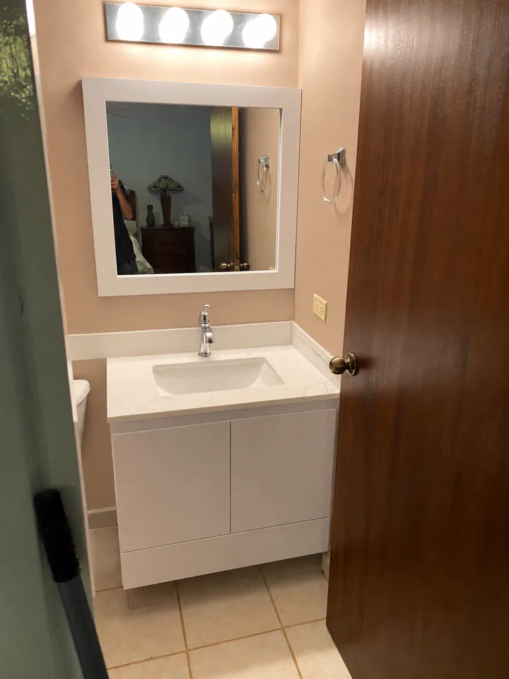 Baño compacto renovado por M5 con mueble blanco, lavamanos bajo cubierta y espejo de marco claro.